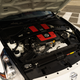 a nissan 370z fairlady nismo with the hood open, zoomed in on the engine